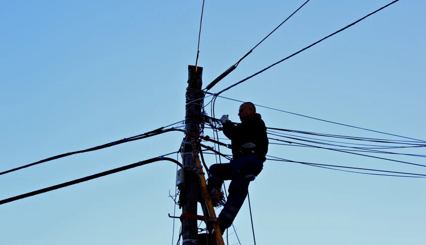 a person standing on a power pole holding a rope