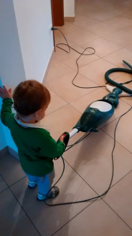 a little boy standing in front of a green power washer