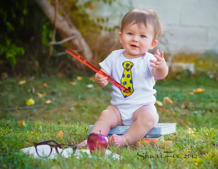 a child in white shirt sitting on grass with a stick