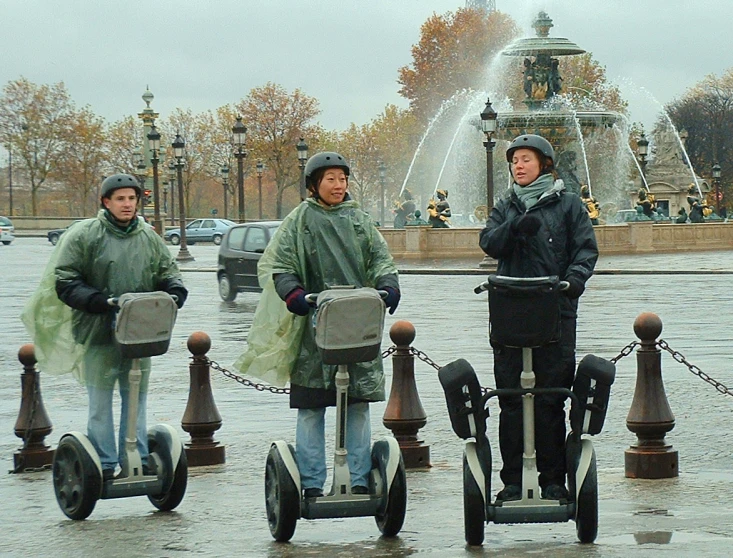 three people in rain gear on hand carts in the rain