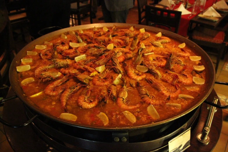 cooked shrimp in tomato sauce on grill with people in background