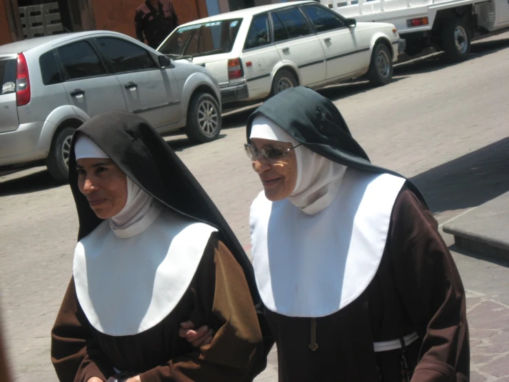 two woman in dresses walk down a road