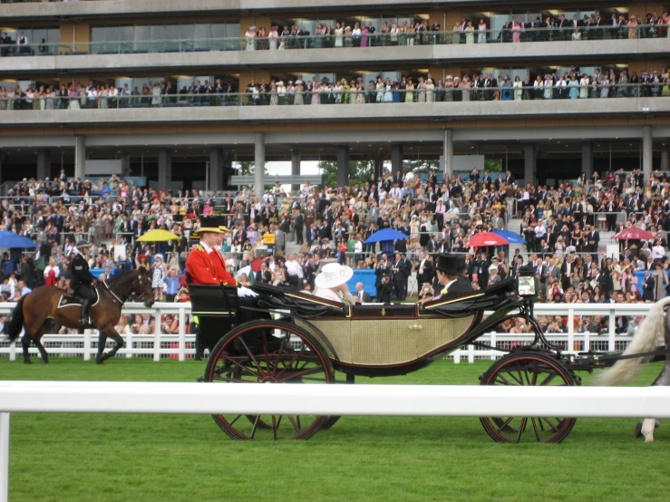 people in the stadium watching people ride horses and carriages