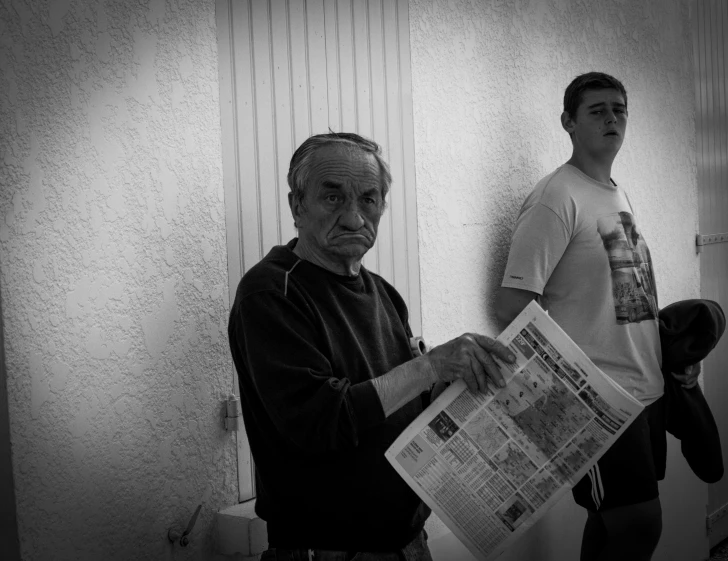 an old man looking at the camera with a newspaper