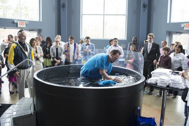 several people gathered around an exhibit with men working on soing in a water tank