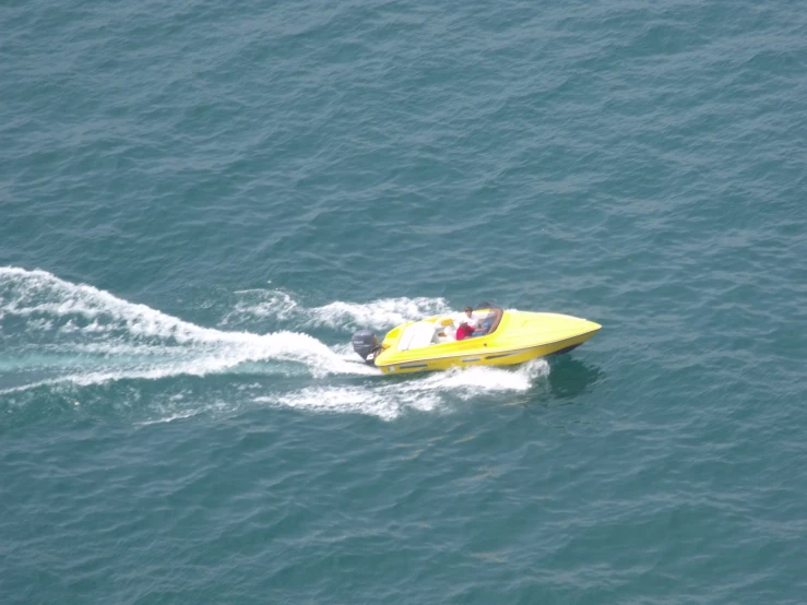 a small yellow speed boat driving across the water