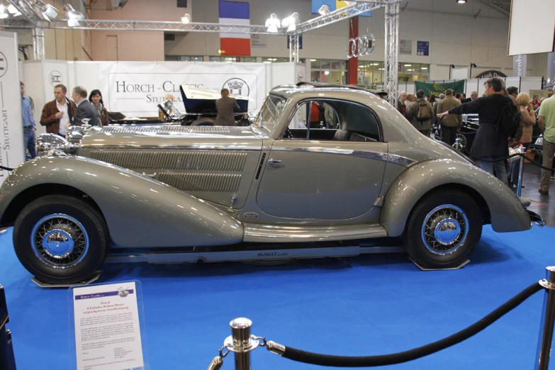 a silver old school sports car is on display