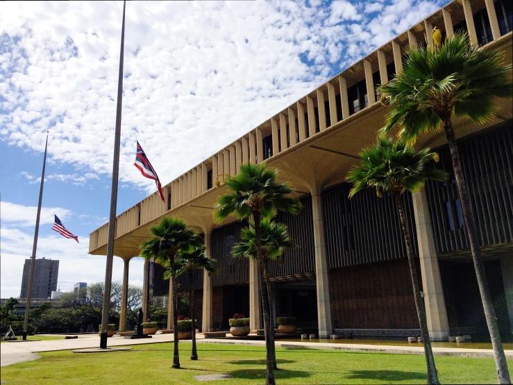 an architectural building with several trees and flagpoles