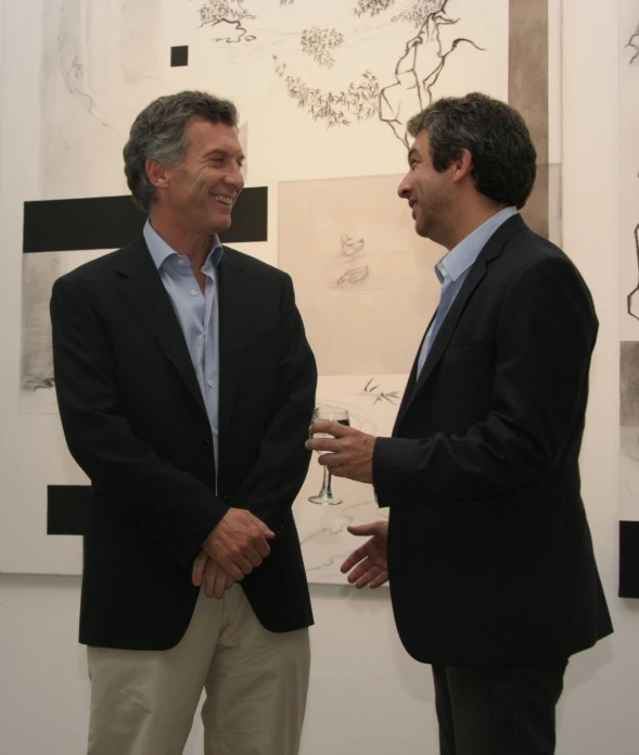 two men in business attire talking at an art gallery