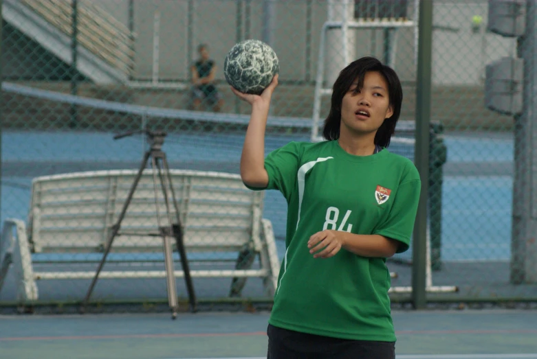 a young person in a green shirt is holding up a ball