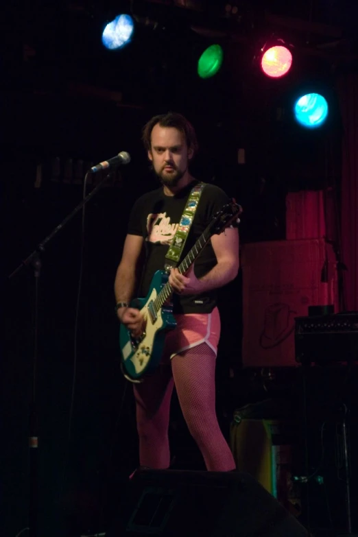 the musician is standing on stage while playing his guitar