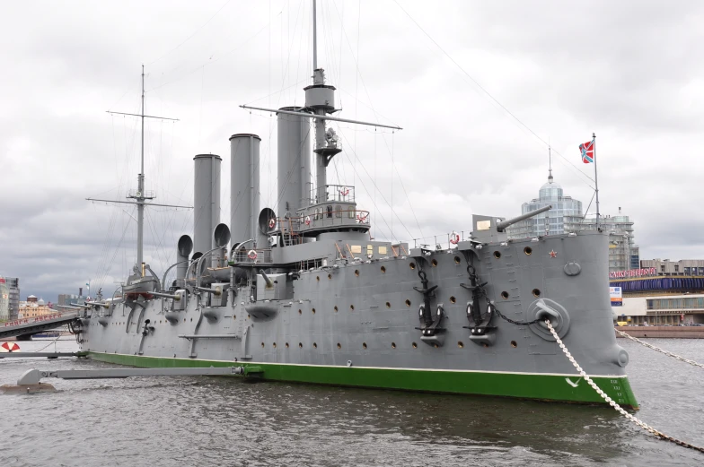 large grey ship with green accents near shore