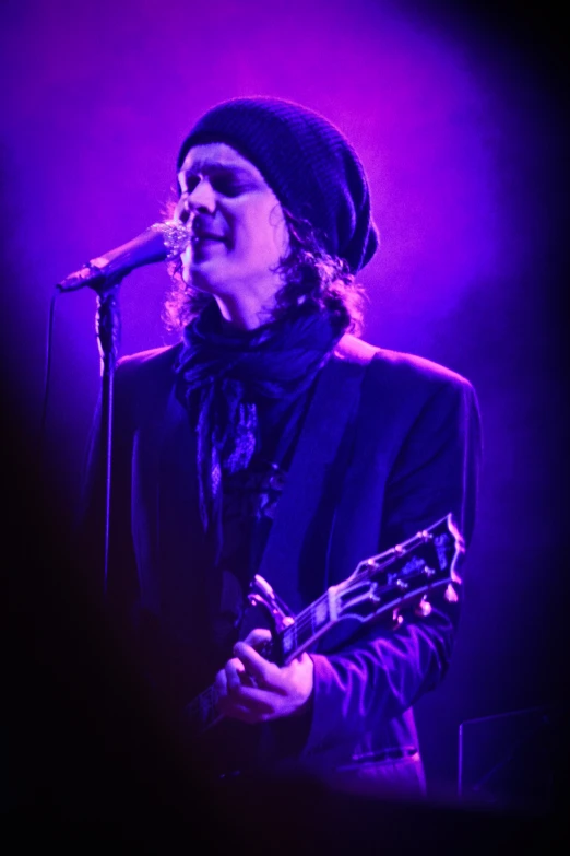 a man standing on stage playing guitar in front of a microphone