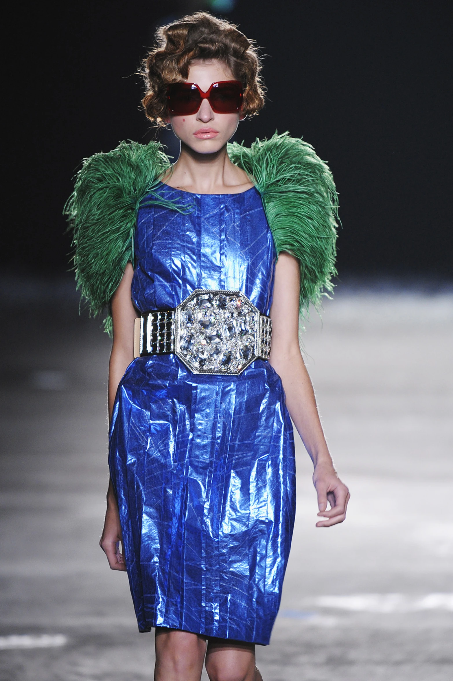 a model wears a blue dress with green feathers