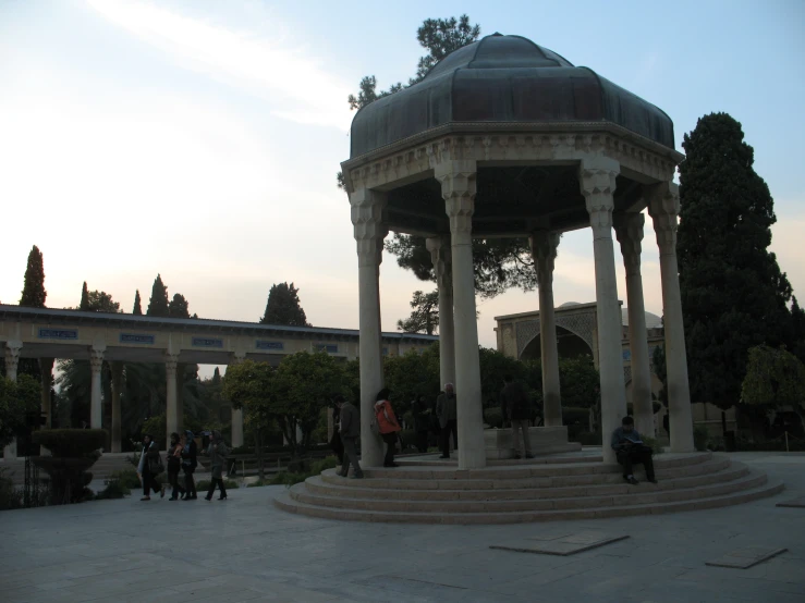 several people are walking around a park with many stone structures