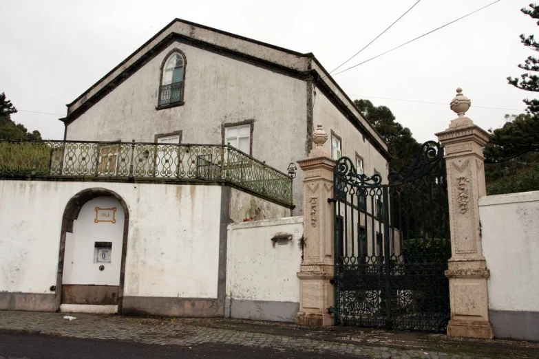 a gate and building with black iron on the front