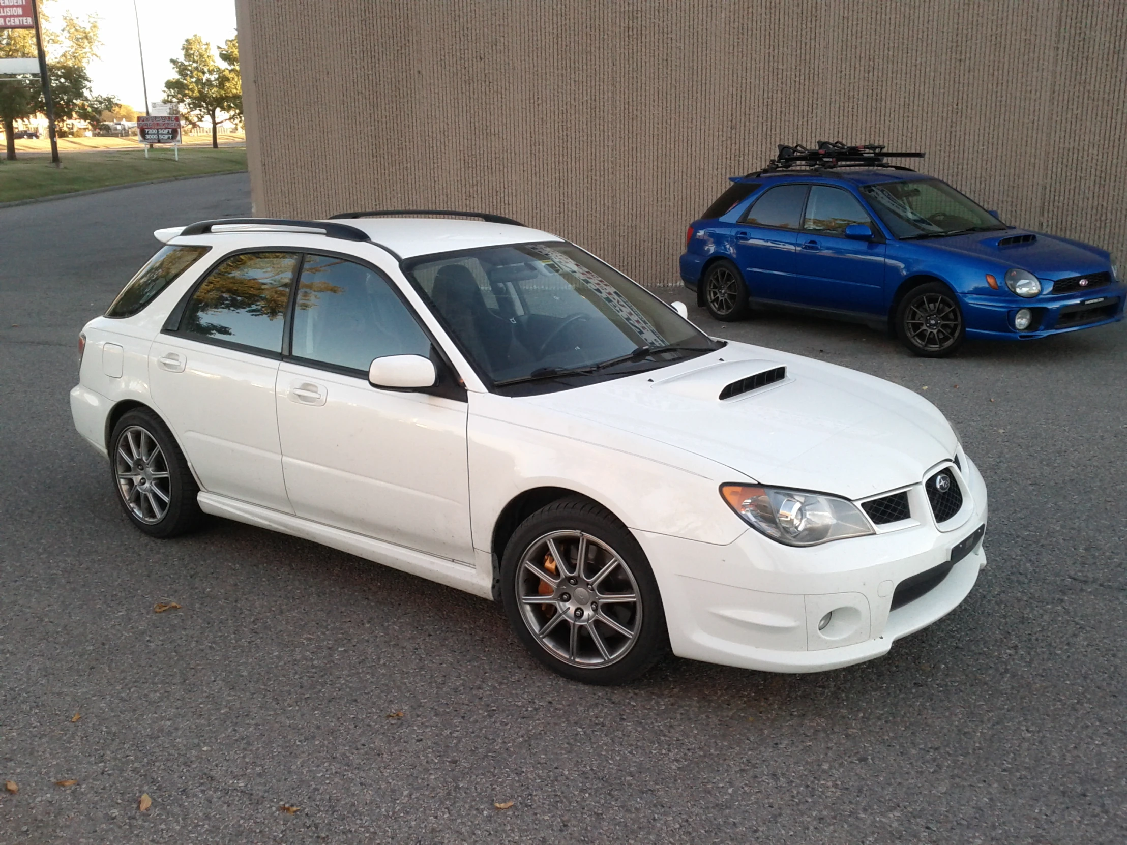 a white sedan parked on the side of a road next to a blue sedan