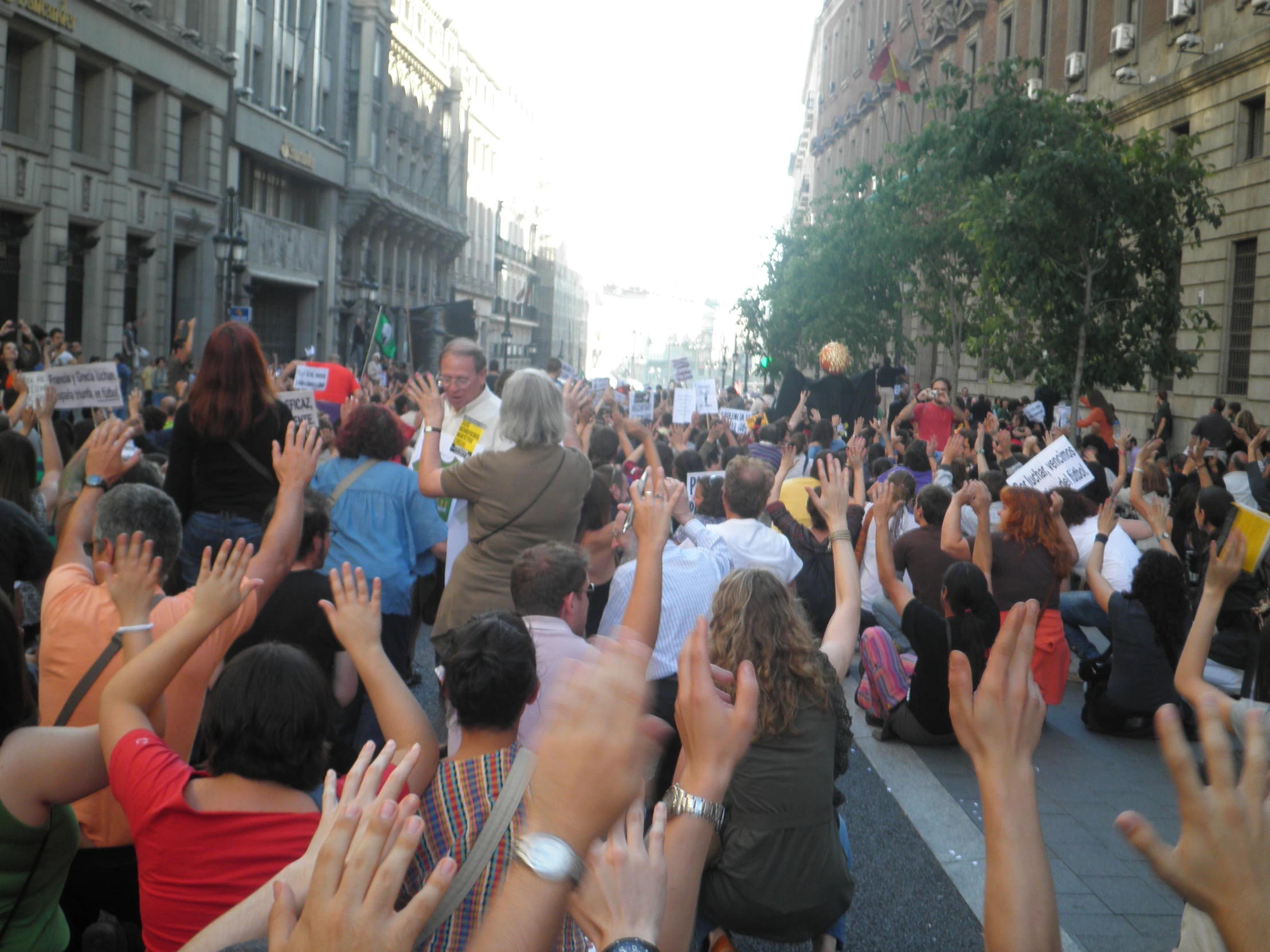 people in the street raising their hands to greet someone with a smile