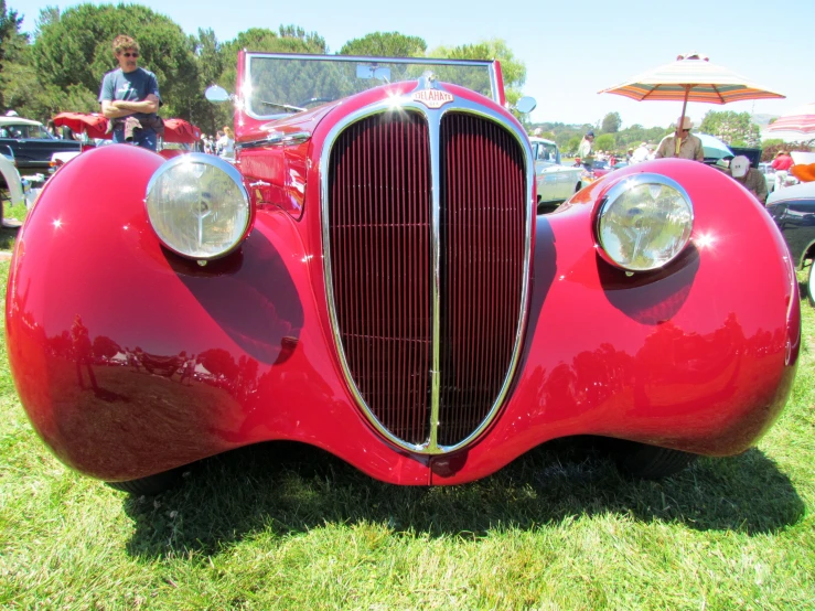 the front view of an old fashioned, red car