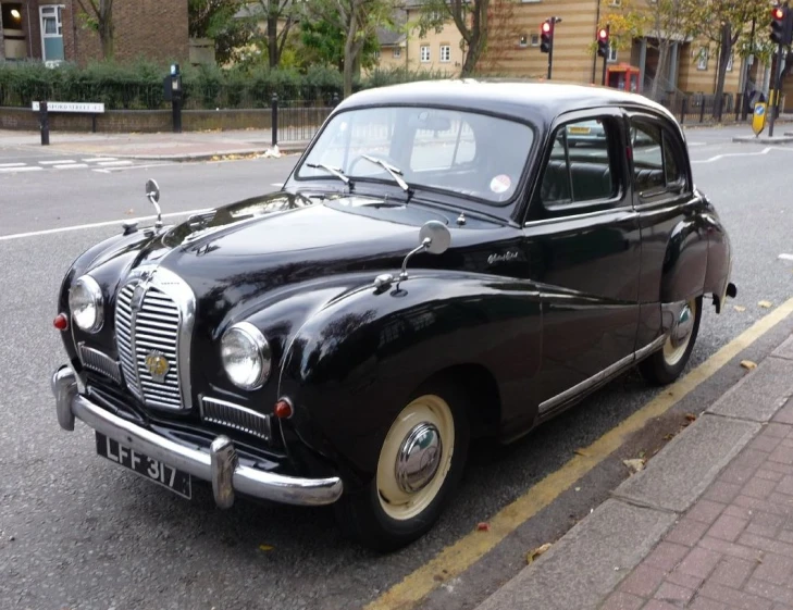 a classic car on the side of a street with another car nearby