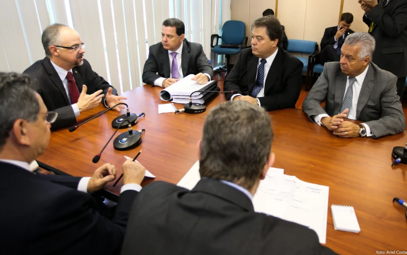 a group of men sitting at a table in front of a microphone