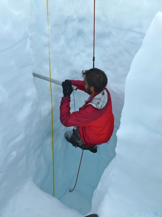 a man on a rope next to an icy mountain