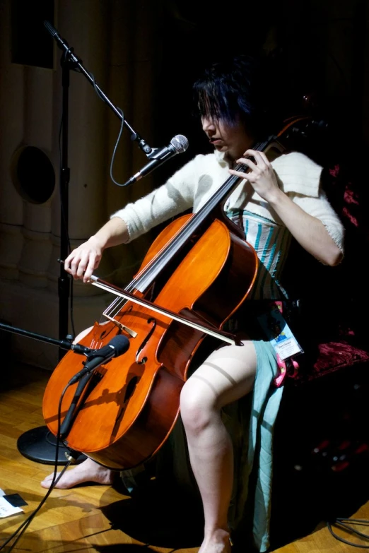 a woman is playing the cello on stage