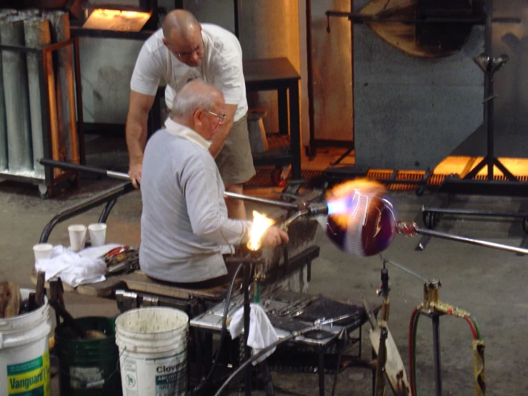 two men in a factory working on a piece of metal