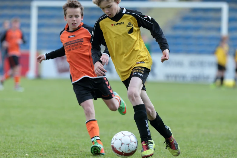 a soccer player kicks the ball while two others watch