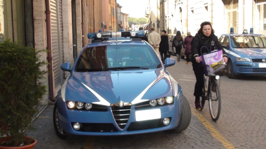 a woman rides her bike past a blue car