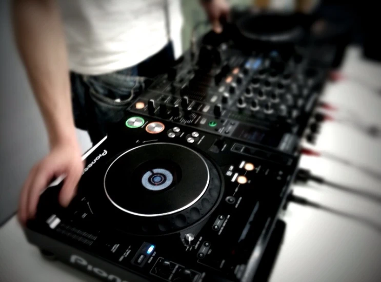 person holding turntable with dj equipment set up