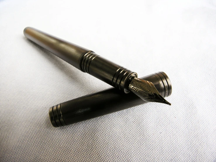 two antique fountain pens are laying on the cloth