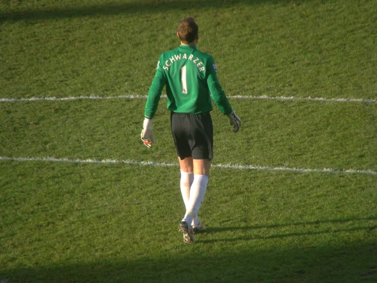 a person wearing a green soccer jersey and black shorts