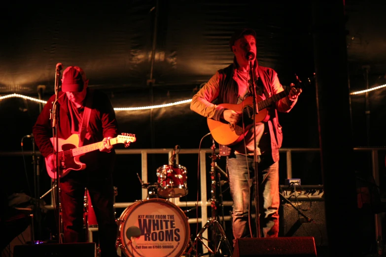 two men playing guitars on stage in the dark