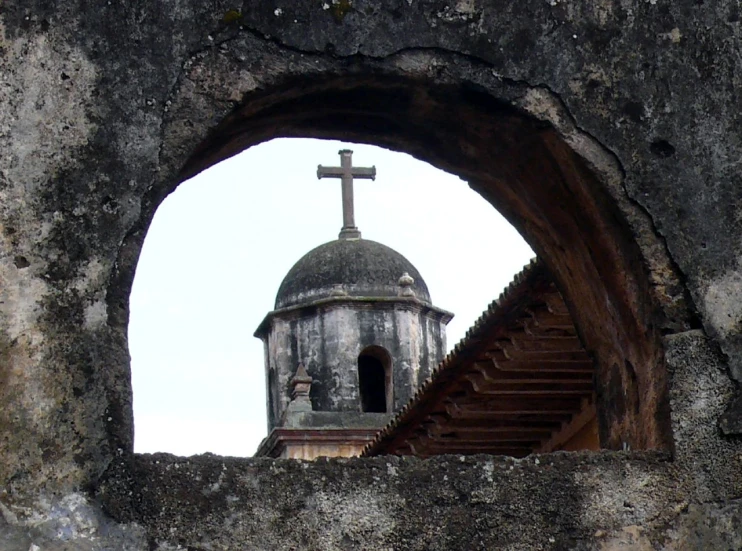 an old building with a tower and cross viewed from a window