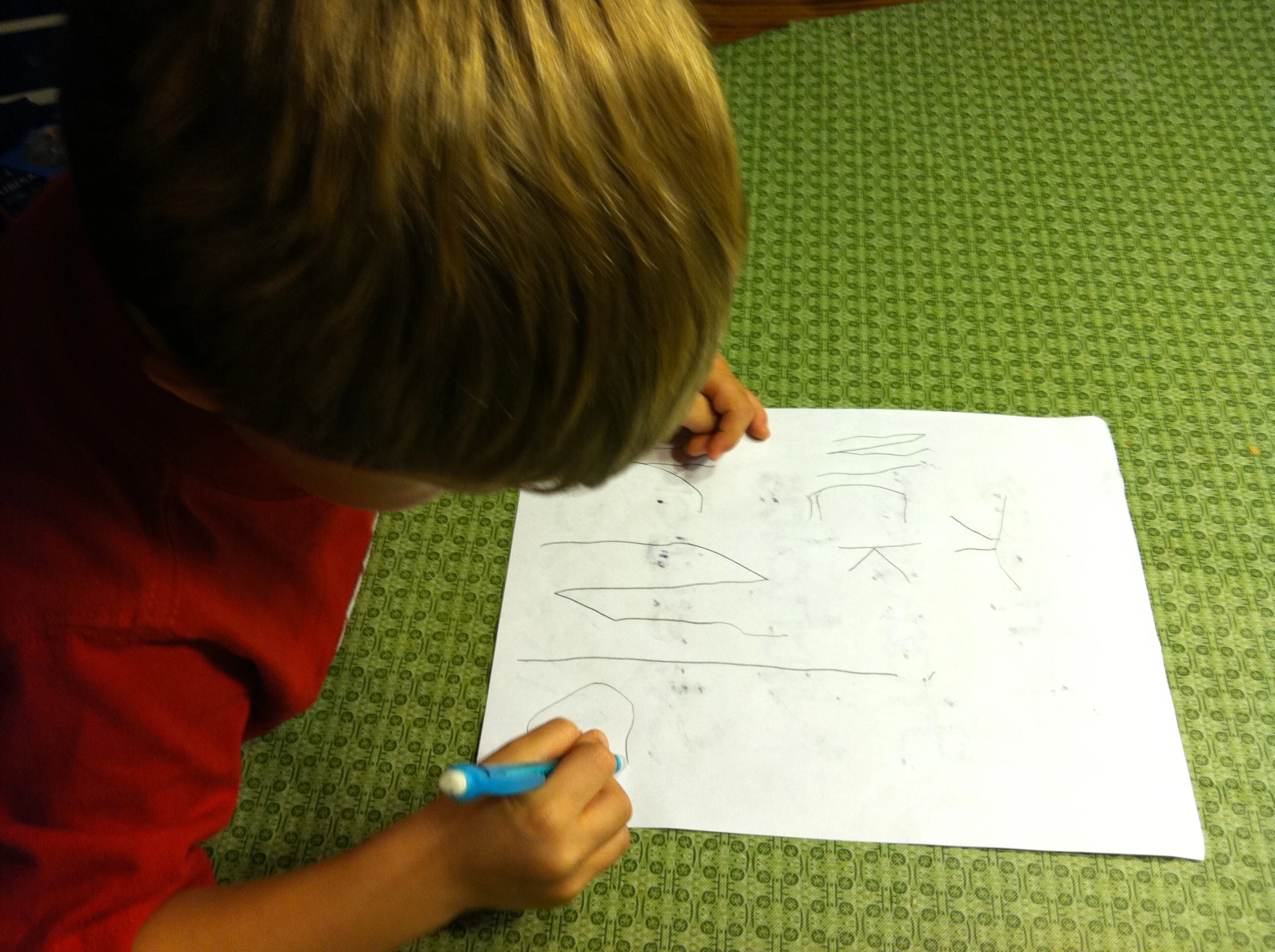 a boy is drawing on the floor and holding a pen