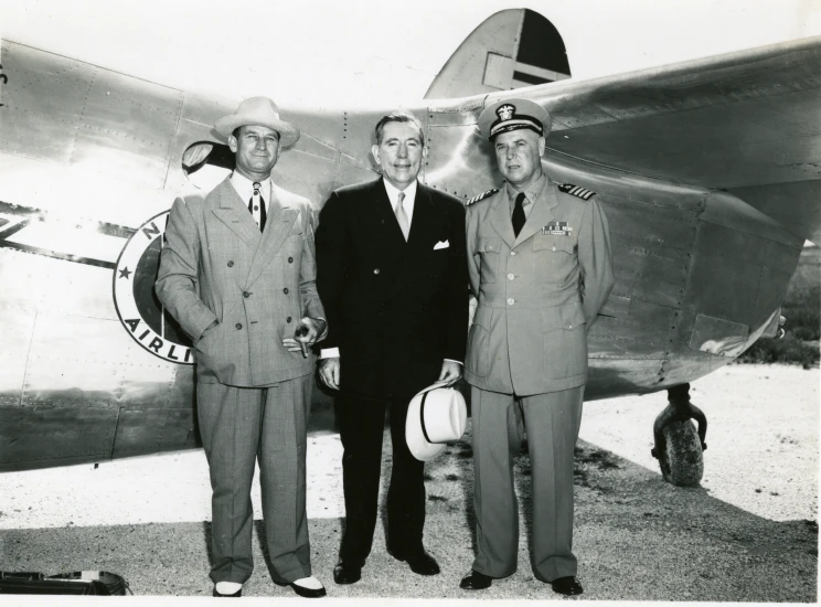 four pilots are standing by an airplane posing for a picture