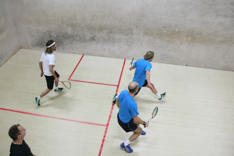 three people holding tennis rackets on a court