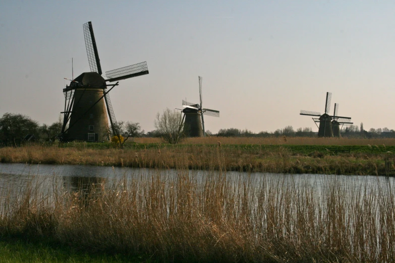 four windmills on the other side of a river