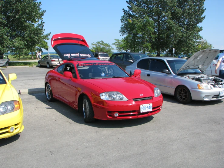 three cars with open hoods sitting in a lot