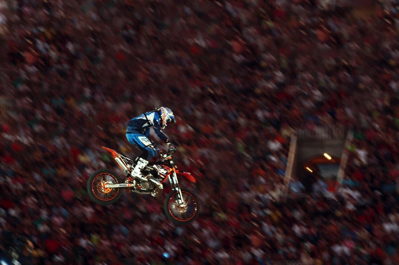 a man on a bike jumps in the air over a crowd