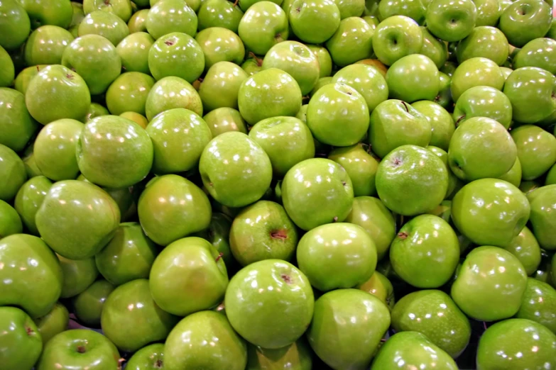 a large pile of green apples for sale
