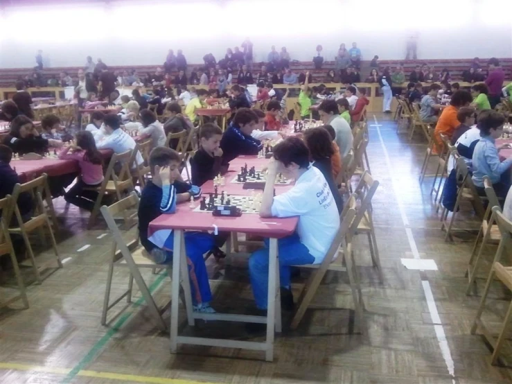 a group of children sitting at tables playing chess