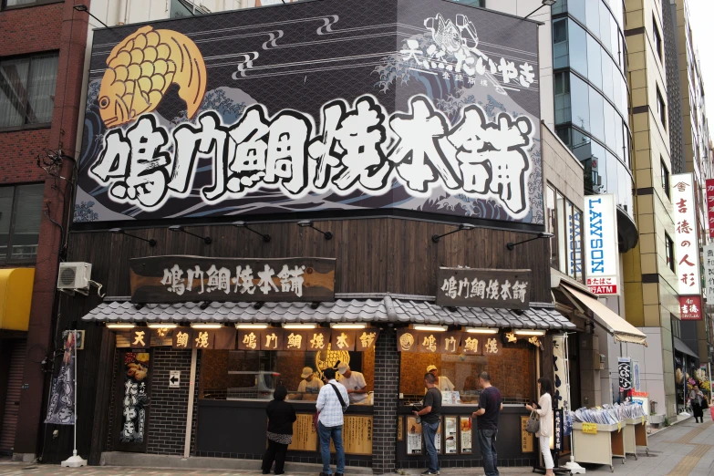 people on sidewalk in front of restaurant on a building