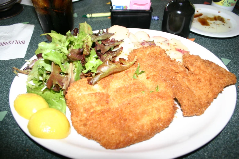 a white plate topped with chicken patties and a salad