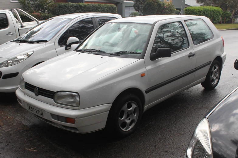 a white car parked next to other cars on a street