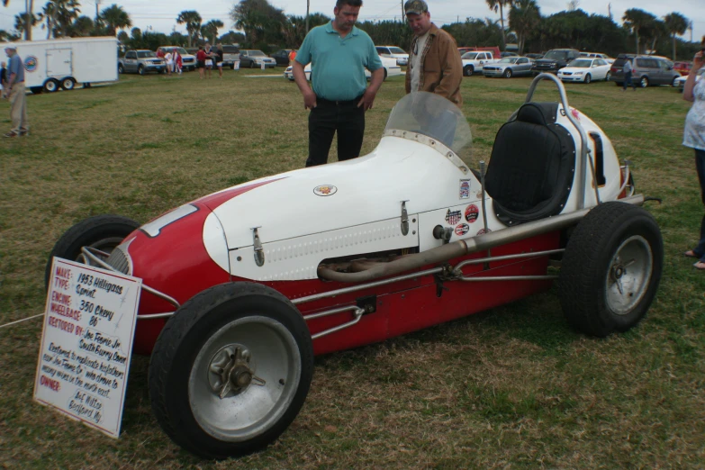 a man and woman look at an old style race car