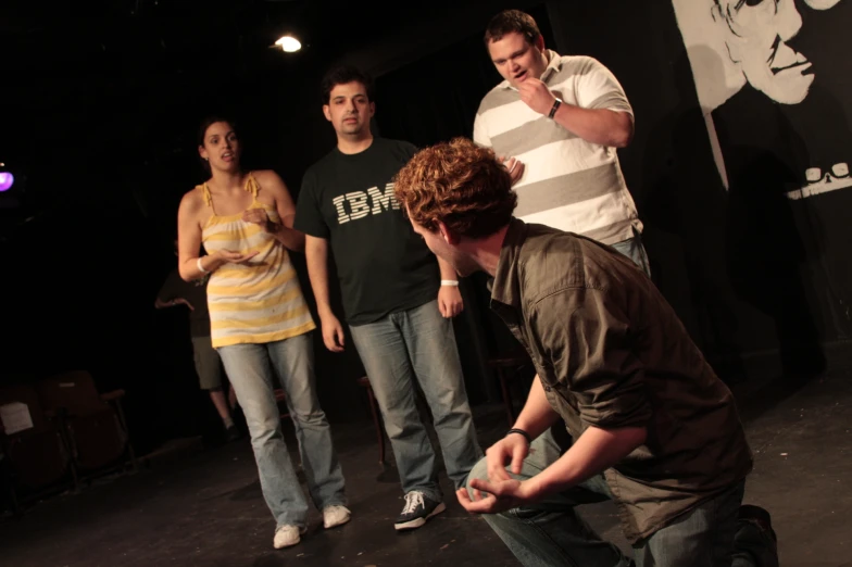 three people are standing on stage as one man talks on the phone