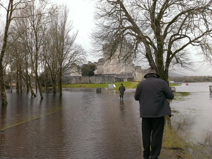 several people walking down a flooded street near trees