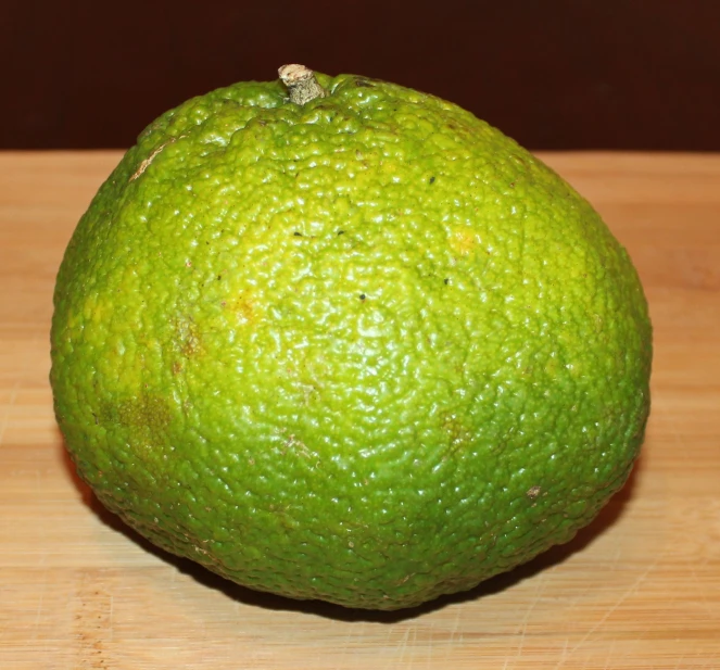a close - up of a green lime sitting on top of a wooden table